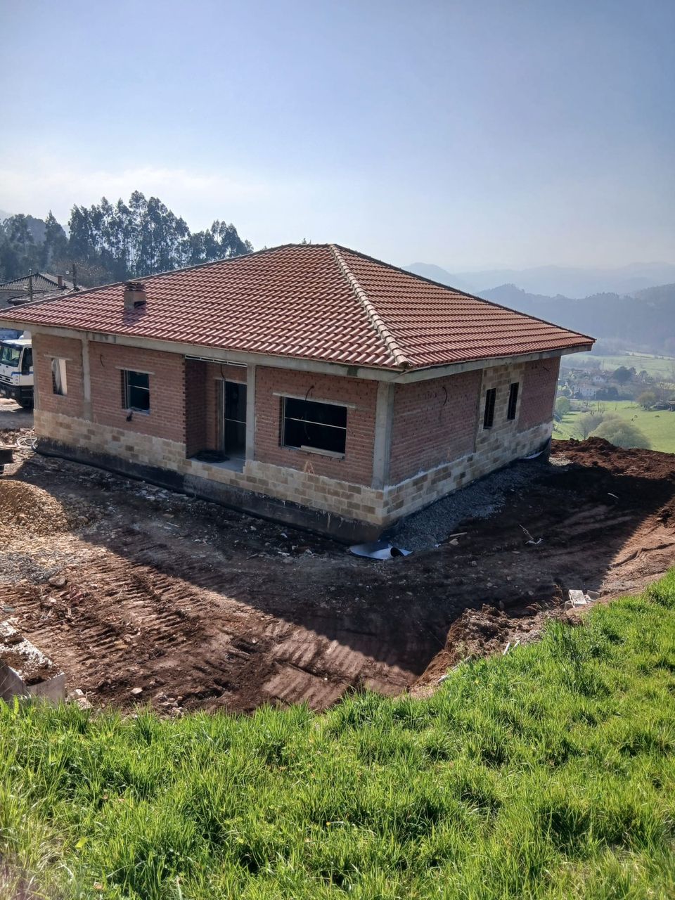 El chalet completo sobre la parcela en ladera: fábrica de ladrillo y cubierta de teja.
