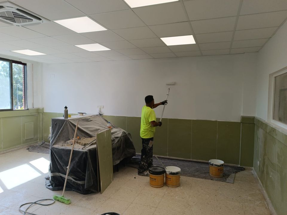 Pintura de un aula con zócalo verde de protección y climatización nueva.