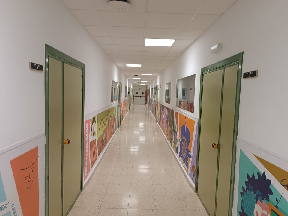 Pasillo de aulas renovado: pintura, iluminación, señalización y suelo reparado.
